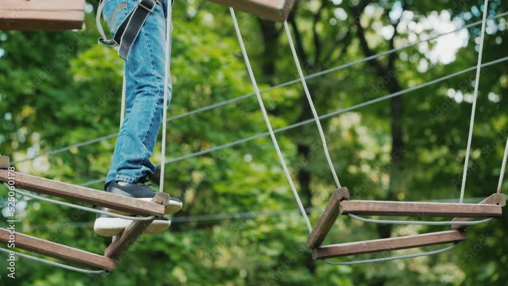 The boy is stuck on a rope obstacle, can not make a step. Overcome the fear concept