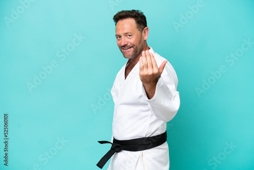 Middle age caucasian man isolated on blue background inviting to come with hand. Happy that you came