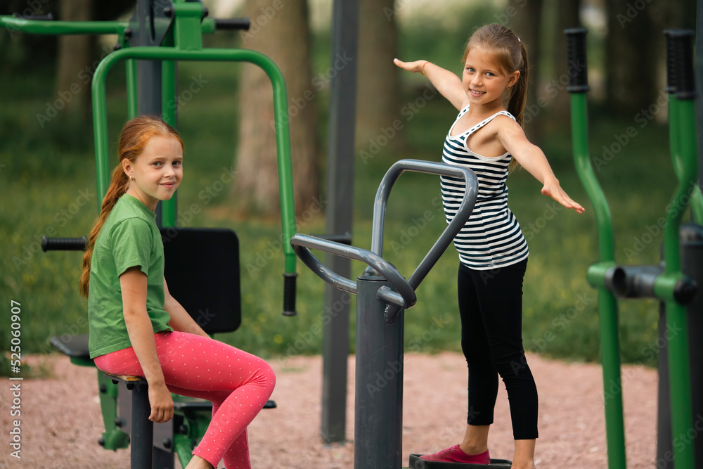 Obraz premium Two teenage girl friends on outdoor fitness equipment.
