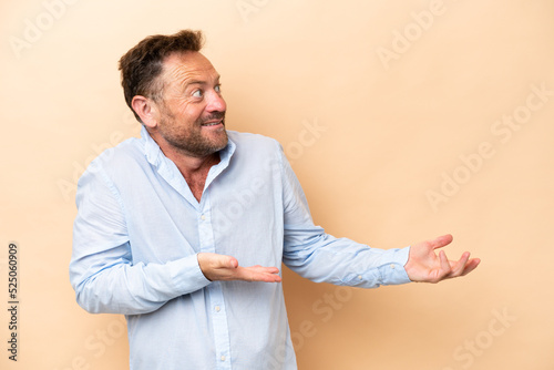 Obraz na plátne Middle age caucasian man isolated on beige background with surprise expression w