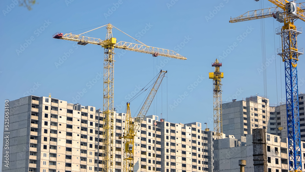 Yellow cranes and high buildings on blue sky background. Skyscrappers under construction. Yellow cranes and high buildings on blue sky background. Skyscrappers under construction.