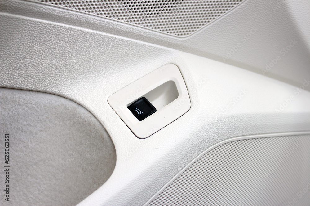 Trunk opening button in a white leather interior of a modern car. Car