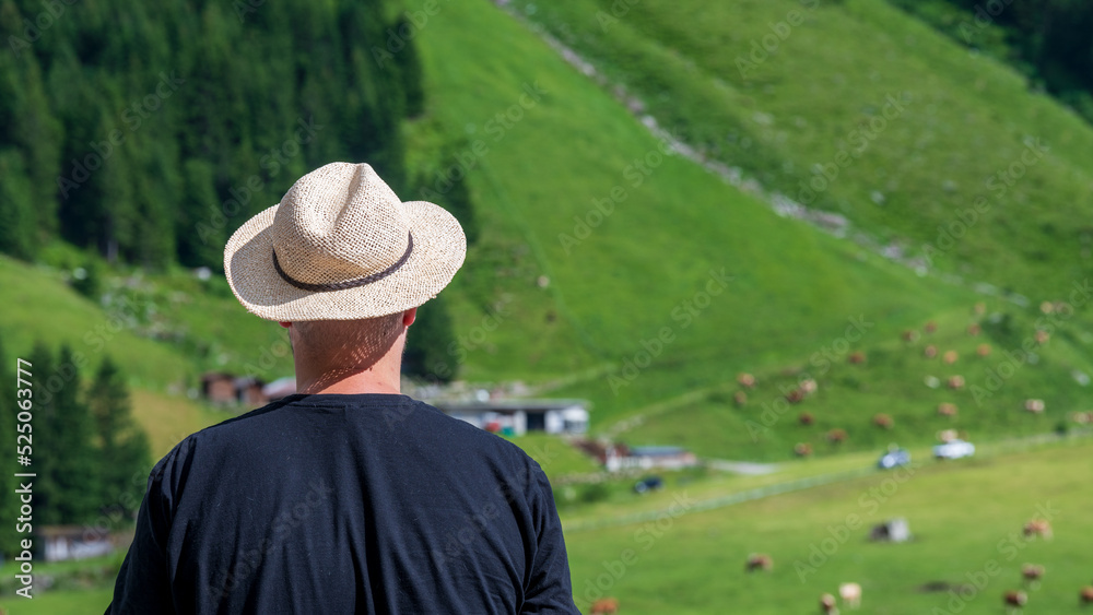 Mann betrachtet eine Rinderfarm und Rinderweiden in den Alpen