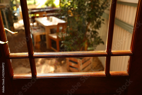 A view through a glass door leading to a patio with chairs and a table.