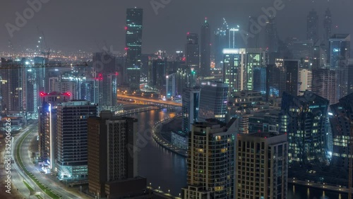 Wallpaper Mural Skyline with modern architecture of Dubai business bay illuminated towers during all night timelapse with lights turning off. Aerial view with canal and construction site Torontodigital.ca