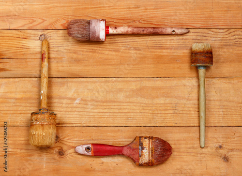 Four old paint brushes on wooden boards. Copy space