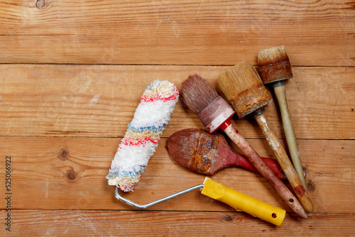 Paint roller and paint brushes on wooden board background