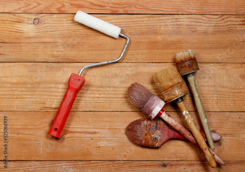 Paint roller and paint brushes on wooden board background