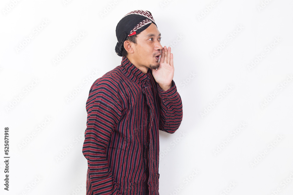 Fototapeta premium asian man with javanese traditional cloth lurik shouting and yelling announcing isolated on white background