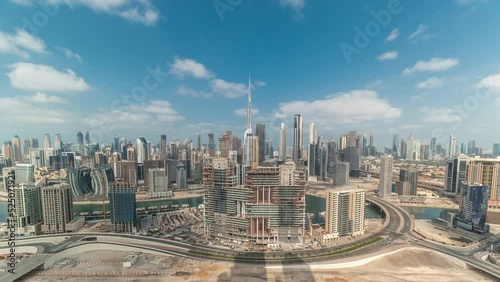 Panoramic skyline of Dubai with business bay and downtown district timelapse. Aerial view of many modern skyscrapers with long shadows and cloudy blue sky. United Arab Emirates. photo