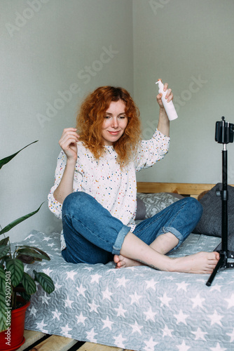 Red haired woman blogger broadcasts live reviews of beauty products for hair