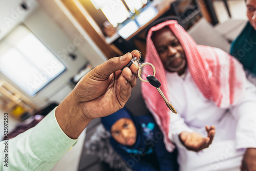 Real estate agent giving happy middle-eastern family key from their new apartment