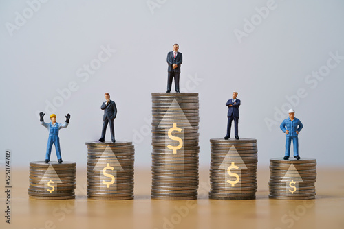 Worker and businessmen miniature figure standing on increasing coins stacking with up arrow and dollar sign for income salary various growth in different position , Human development concept.
