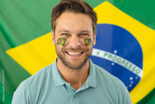 Image of happy caucasian man with flags of brazil on face over flag of brazil
