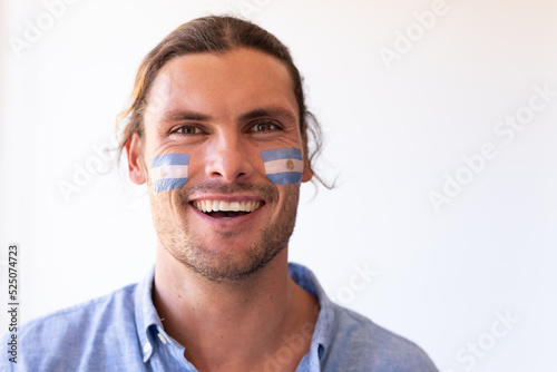 Image of happy caucasian man with flags of argentina on face