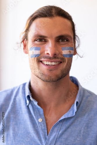 Vertical image of happy caucasian man with flags of argentina on face