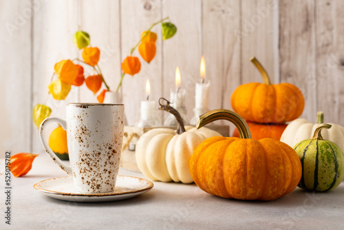 Autumn still life with cup of tea, pumpkins,flowers and candles on table.Than...