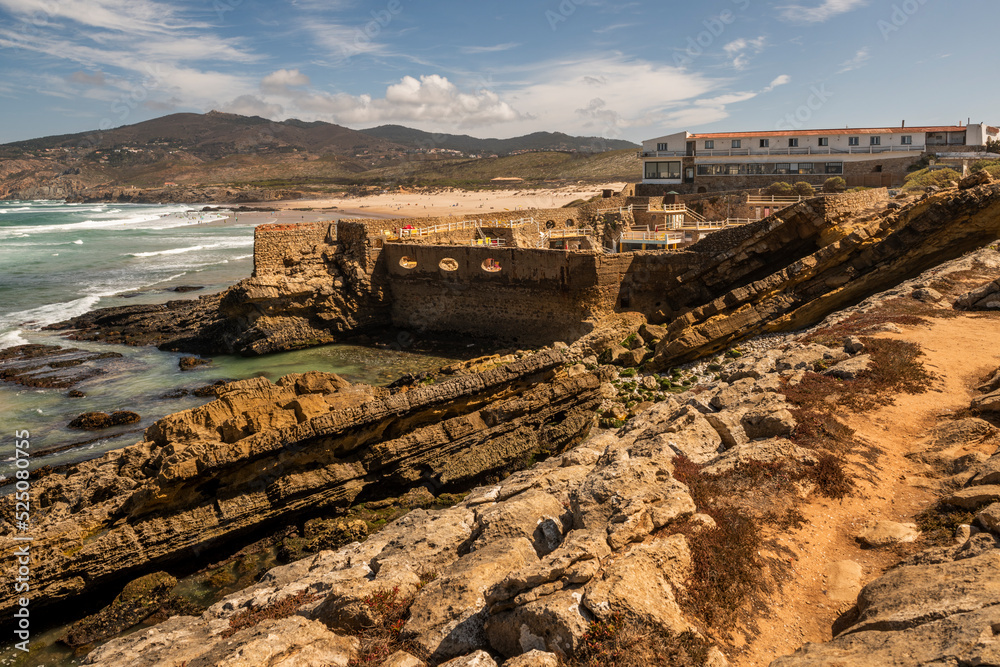Loose rock cliff and persistent waves on the Portuguese Atlantic coast with a terraced hotel among the rocks