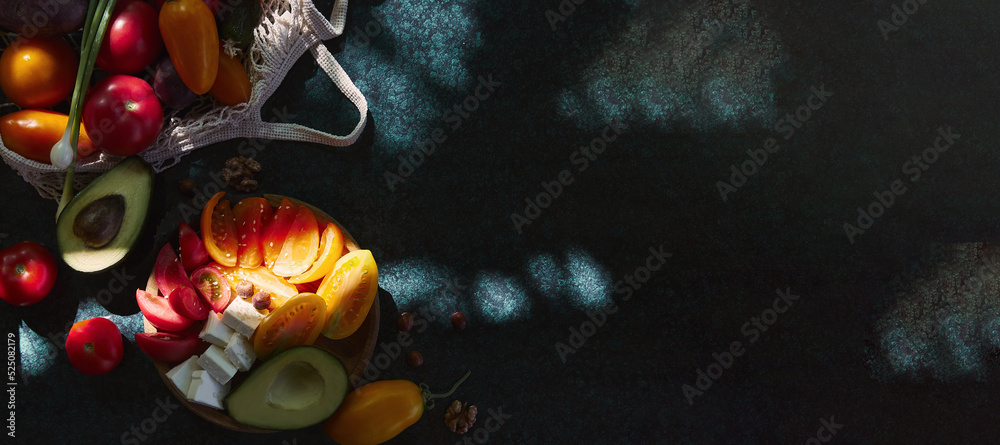 Healthy seasonal salad with vegetables, feta cheese, avocado. Onion, yellow, red tomatoes, pepper in eco shopping bag under trendy hard shadows with reflection. Extra wide banner. Copy space.