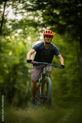 Young man with his mountain bike going for a ride past the city limits in a lovely forest, getting the daily cardio dose