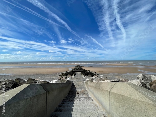 Steps leading onto a beach with large rocks and a blue sky background. Taken in Fleetwood Lancashire England.  photo