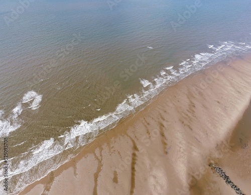 Aerial view looking down onto a beach with waves crashing. Taken in Fleetwood Lancashire England. 