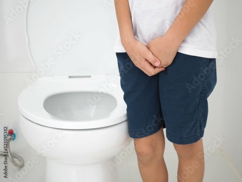 Child stood in the bathroom. With severe ache pee. Closeup photo, blurred.