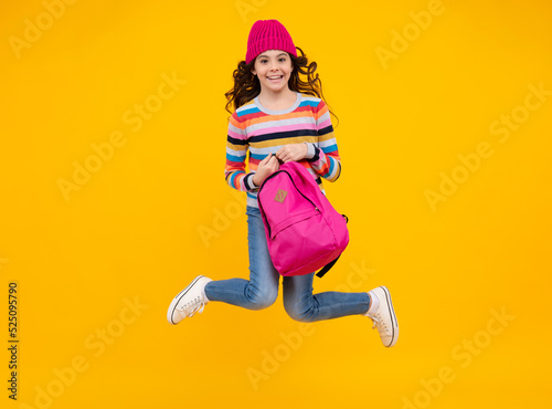 Autumn school. Teenager school girl with backpack in autumn clothes on yellow isolated studio background. Happy teenager, positive and smiling emotions of teen girl