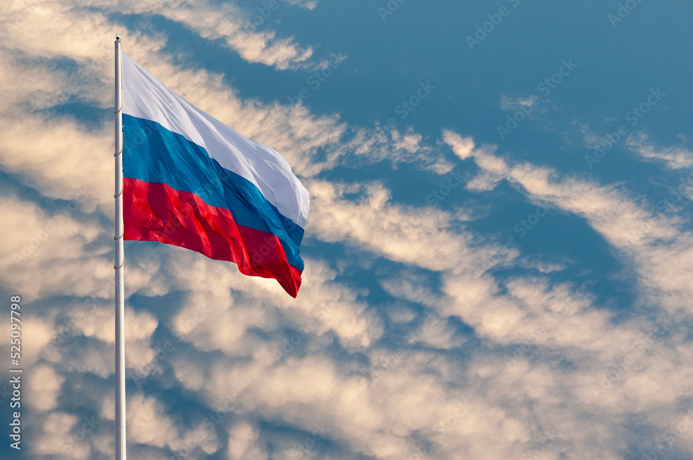 Waving Russian flag against a blue sky with clouds and empty space for text. Room for text. National flag of the Russian Federation