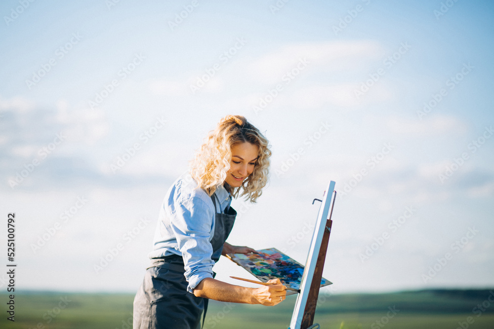 Woman artist painting with oil paints in a field Woman artist painting with oil paints in a field