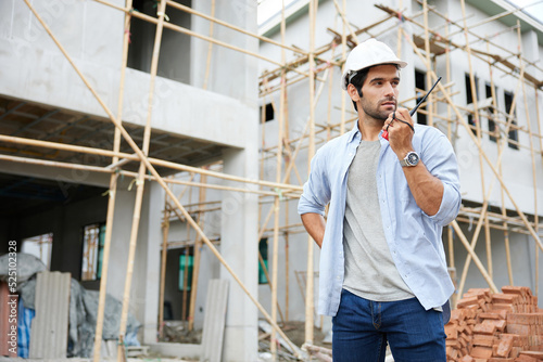 worker or architect using walkie talkie and talking to someone at construction site