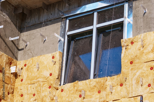 Plastic double glazing in a new house. Insulation of the facade of a house under construction using modern technologies using mineral wool. Preparing for a cold winter in an energy crisis photo