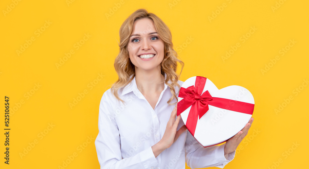 happy woman with present heart box on yellow background happy woman with present heart box on yellow background