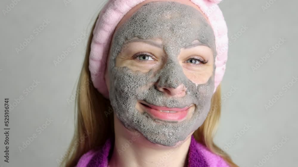 girl with blond hair and European appearance ,close-up on the face .Smiling gray bubble face mask on her face.the concept of home care milking the girls girl with blond hair and European appearance ,close-up on the face .Smiling gray bubble face mask on her face.the concept of home care milking the girls