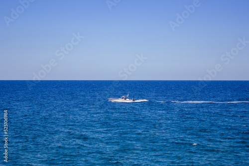 Motorboat on the horizon with calm seas in the mediterranean sea and ocean
