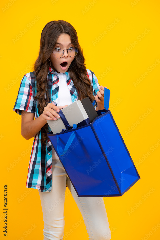 Child girl hold shopping bag enjoying sale isolated on yellow background. Portrait of teenager girl is ready to go shopping. Shocked surprised teenager girl. Child girl hold shopping bag enjoying sale isolated on yellow background. Portrait of teenager girl is ready to go shopping. Shocked surprised teenager girl.