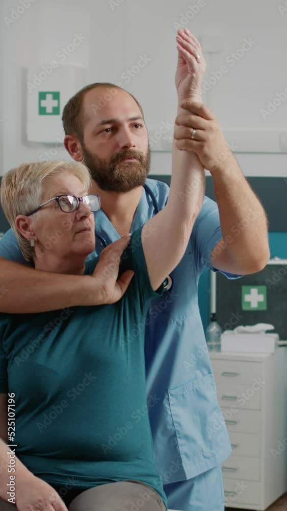 Vertical video: Orhopedic specialist doing arms stretch exercise with elder patient, helping with physical therapy. Male osteopath giving assistance to senior woman, recover from mechanical disorders. Vertical video: Orhopedic specialist doing arms stretch exercise with elder patient, helping with physical therapy. Male osteopath giving assistance to senior woman, recover from mechanical disorders.