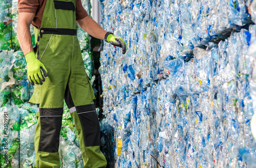 Waste Management Worker in Front of a Pile of Pressed Plastic PET Bottles photo