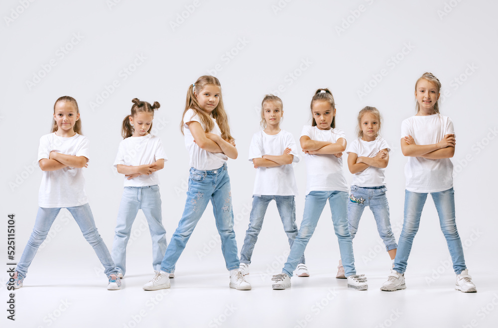 Dance group of happy, active little girls in jeans and t-shirts dancing isolated on white studio background. Concept of music, fashion, art, childhood, hobby Dance group of happy, active little girls in jeans and t-shirts dancing isolated on white studio background. Concept of music, fashion, art, childhood, hobby