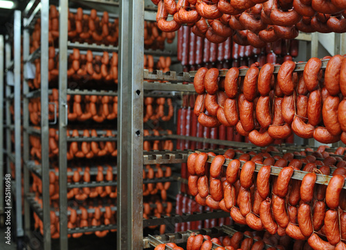 a lot of smoked sausages on the metal shelves of the racks of the meat factory. Food production