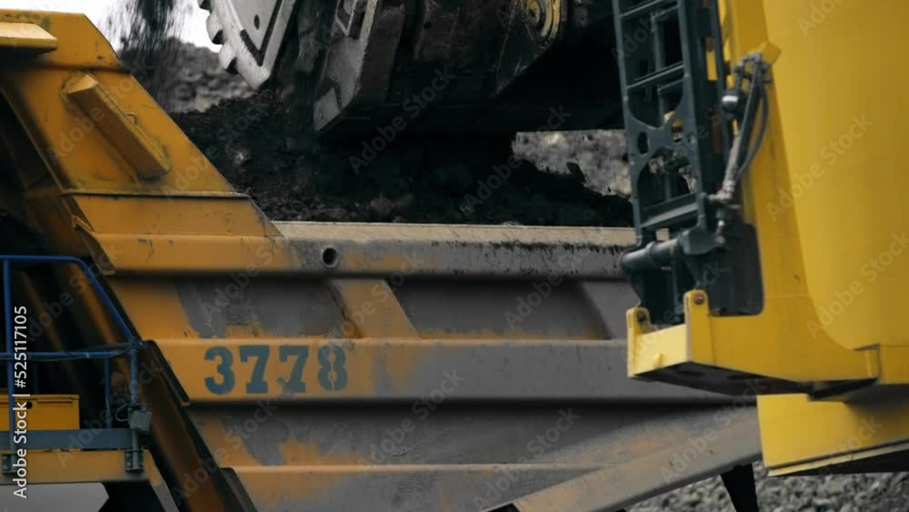 A large bucket opens and ore and soil are offloaded into the dump truck. Mining industry. A quarry. Ore mining. 4K A large bucket opens and ore and soil are offloaded into the dump truck. Mining industry. A quarry. Ore mining. 4K