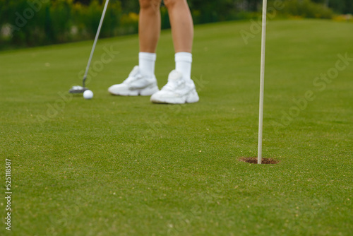 Woman in white short skirt practicing golf on the green
