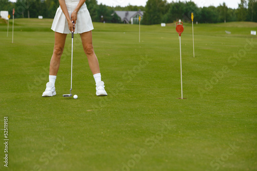 Woman in white short skirt practicing golf on the green © vladdeep