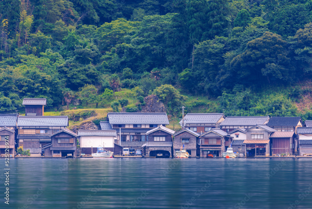 Traditional wooden boathouses of small fishing village line shore in calm bay