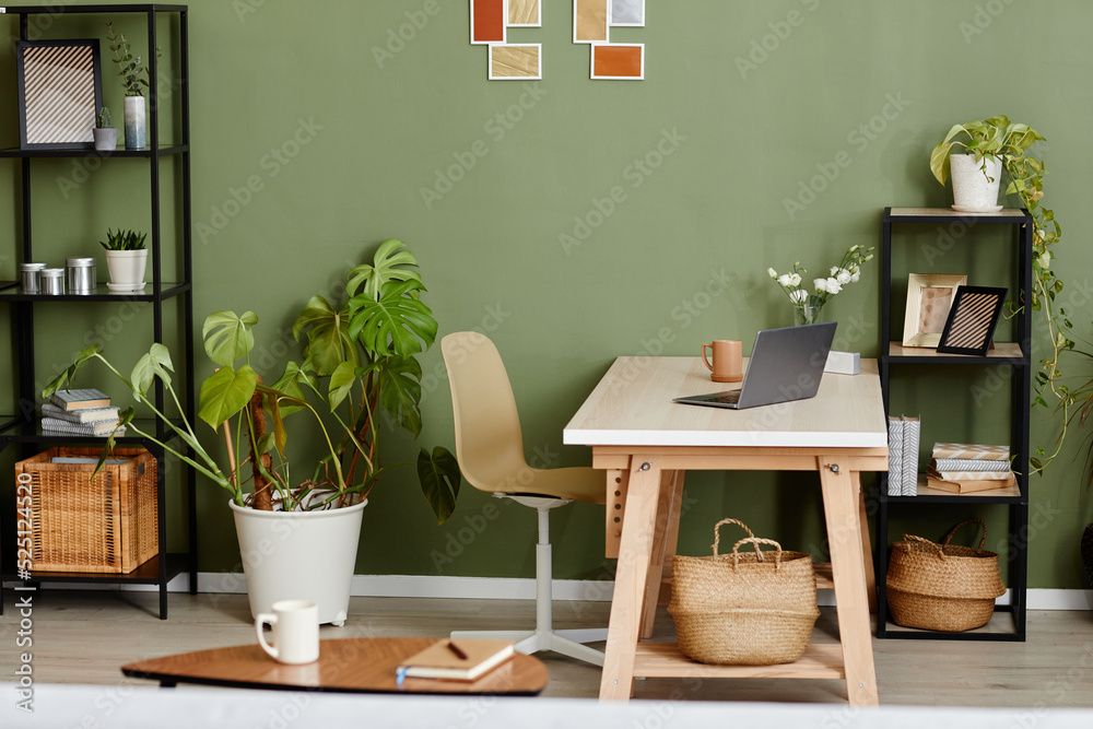 Horizontal image of domestic room with green plants and workplace with laptop in the middle for online work Horizontal image of domestic room with green plants and workplace with laptop in the middle for online work