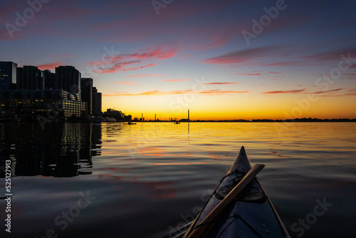 Photography A sea kayaker waits for the sun to break the horizon on Toronto's Inner Harbour early on a summer morning