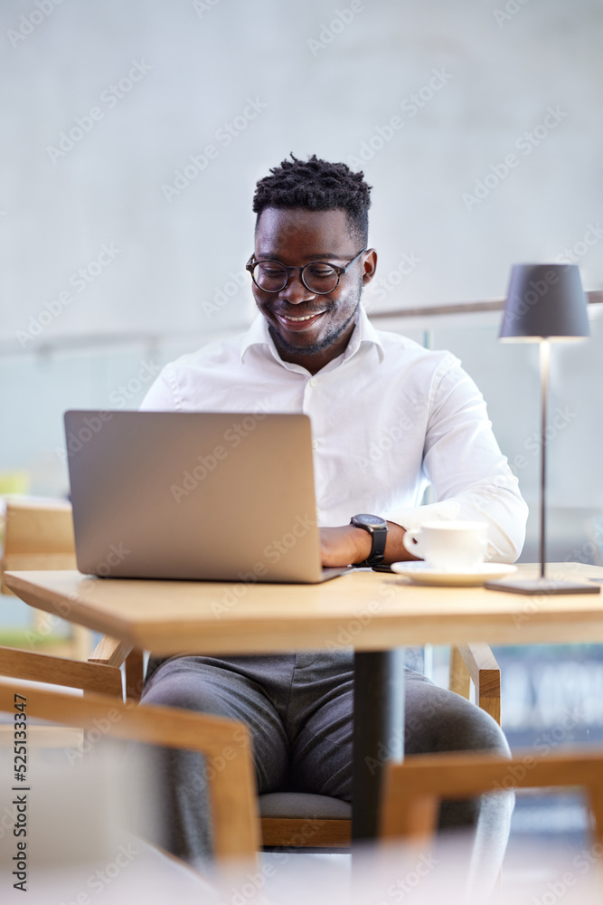 A freelancer is typing on the keyboard while smiling at the laptop in the cafeteria. A freelancer is typing on the keyboard while smiling at the laptop in the cafeteria.