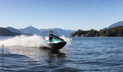 Adventurous Caucasian Woman on Water Scooter riding in the Ocean. Howe Sound and mountain landscape in background. West Vancouver, British Columbia, Canada. © edb3_16