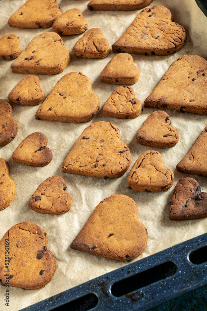 Heart shaped biscuits with chocolate drops on a baking tray. Heart shaped biscuits with chocolate drops on a baking tray.