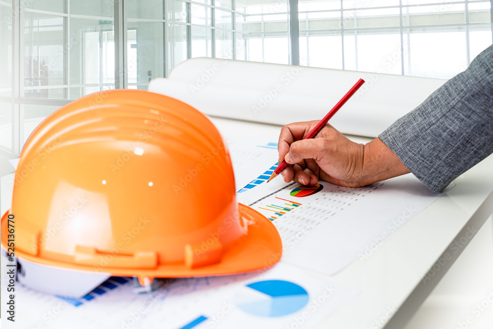 Asian engineer with architectural house plan project blueprint, graph ...